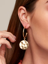 Load image into Gallery viewer, Matte metal hoop earrings with a hammered medallion charm drop
